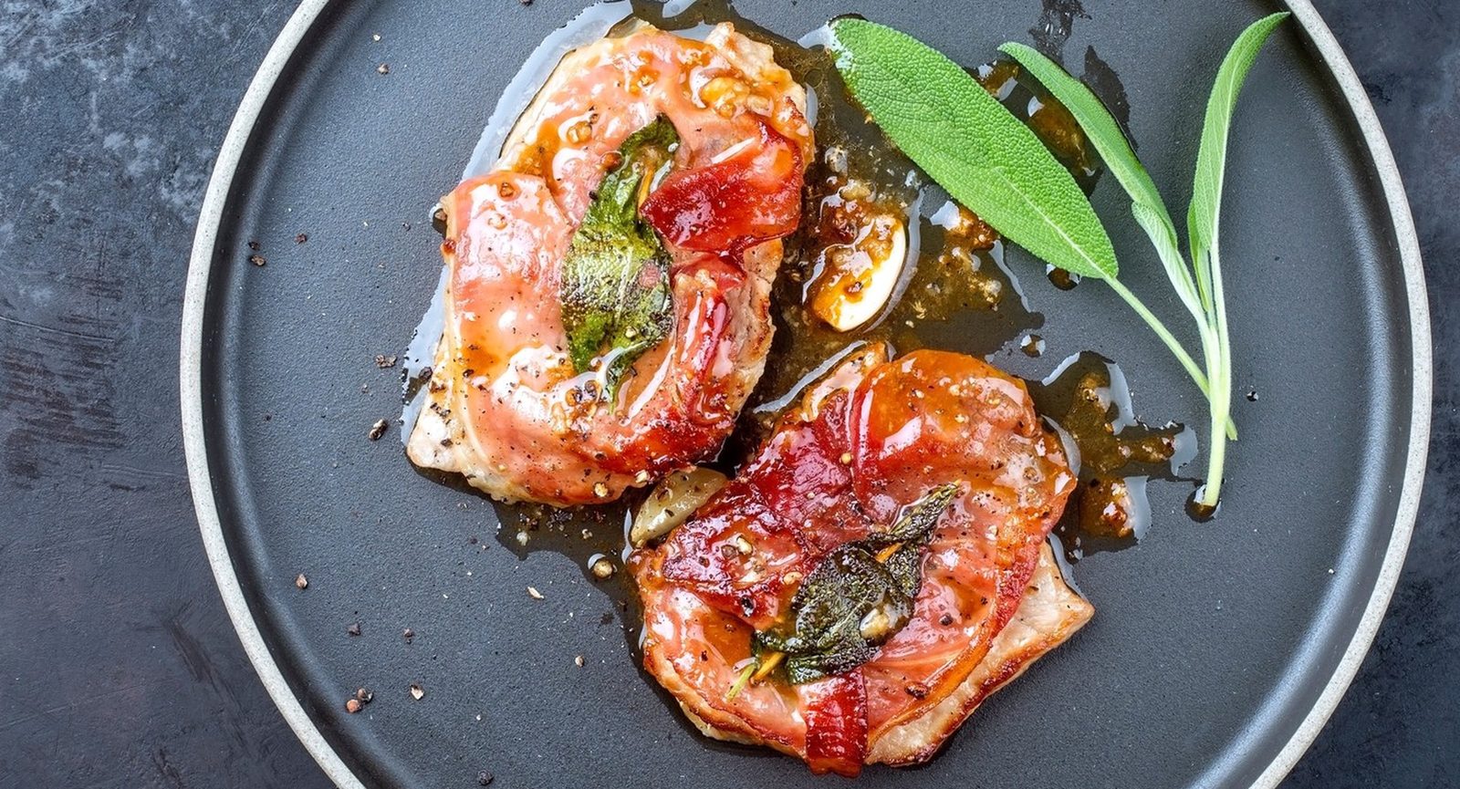 Saltimbocca vom Reh mit Salbei und Schinken auf einem dunklen Teller